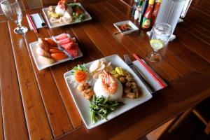 tres platos de comida en una mesa de madera en Bunaken Cha Cha Nature Resort, en Bunaken