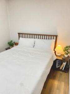 a large white bed with a wooden headboard and a lamp at Sam Stay in Hyomoktong-Ilgu