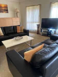 Una sala de estar con un sofá de cuero negro y una mesa de café. en Spacious Williamstown Apartment with Free Parking, en Williamstown