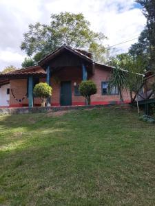 a red house with a green yard in front of it at Chácara Pedacinho do Céu in Extrema