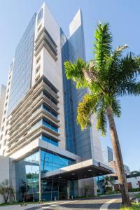 a tall building with a palm tree in front of it at Flat dentro de hotel de Luxo proximo ao shopping in Manaus