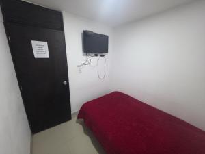 a bedroom with a red bed and a black cabinet at Hospedaje & Restaurante Rancho Grande Tocancipá SAS in Tocancipá