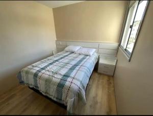 ein kleines Schlafzimmer mit einem Bett und einem Fenster in der Unterkunft Hospedagem Apto Residencial Canela in Canela