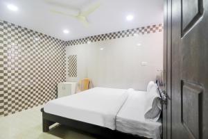 ハイデラバードにあるHotel O Aroma Classic Near Nampally Railway stationの白いベッドとチェック入りの壁が備わるベッドルーム1室が備わります。