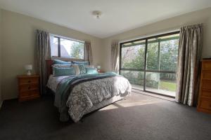 a bedroom with a bed and a large window at 8b Rippingale Road in Hanmer Springs