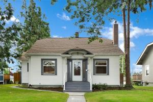 a white house with a blue door and trees at Historic Front Street Home in Lynden