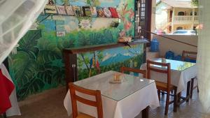 a restaurant with a table and a cat sitting on a wall at Pousada Chez Nous in Penedo