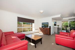 a living room with red furniture and a flat screen tv at Waitui 1 - 3 Somerset Street in Byron Bay