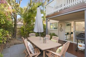 a table with chairs and an umbrella on a patio at Waitui 1 - 3 Somerset Street in Byron Bay