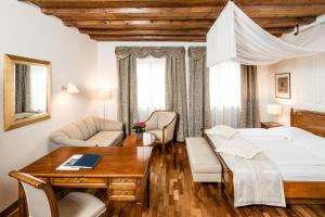 a bedroom with a bed and a desk and a table at Hotel Restaurant Lilie in Vipiteno