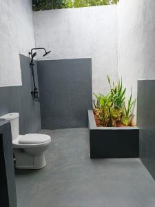 a bathroom with a toilet and plants in it at Jungle Baum Villa Habarana in Hiriwadunna