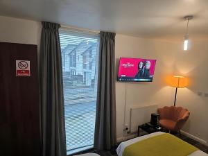 a hotel room with a tv and a bed and a window at MetroStay Manchester in Manchester +22 photos