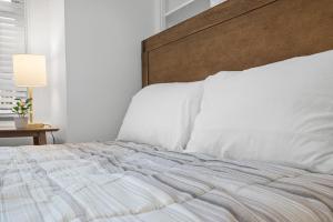 a bed with white sheets and a wooden headboard at Pittsburgh Shadyside 2E Bright Modern Private Bedroom with Shared Bathroom in Pittsburgh