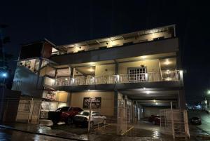 un bâtiment avec des voitures garées dans un parking la nuit dans l'établissement Platinum Hotel, à Tegucigalpa