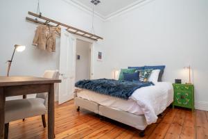 ein Schlafzimmer mit einem Bett, einem Schreibtisch und einem Tisch in der Unterkunft The Blue Door Heritage 2BR Cottage in CBD in Adelaide