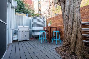 eine Terrasse mit zwei blauen Hockern und einem Tisch und einem Baum in der Unterkunft The Blue Door Heritage 2BR Cottage in CBD in Adelaide
