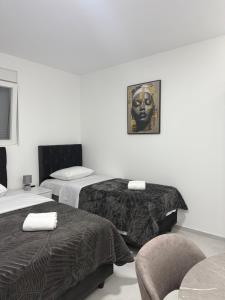 a hotel room with two beds and a chair at Apartmani Zabjelo in Podgorica