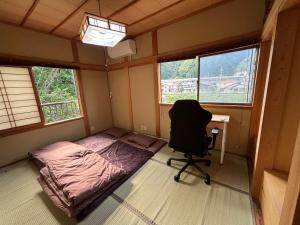 a bedroom with a bed and a desk and a chair at 民泊浜田 蛍の里 in Hamada