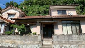 a small house with a stone wall at 民泊浜田 蛍の里 in Hamada