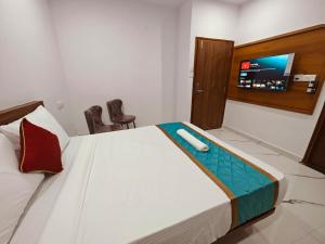 a bedroom with a bed with a tv on the wall at Keerthis Comforts Bengaluru Airport Hotel in Bengaluru