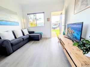 Una sala de estar con un sofá y un televisor de pantalla plana. en Blue Palms Cottage, en North Haven