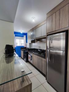 een keuken met een roestvrijstalen koelkast en houten kasten bij Apartamento aconchegante in Balneário Camboriú