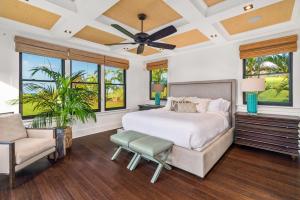 a bedroom with a bed and a chair and windows at Luxury 6BR Ocean View Estate Home in Kukuiula in Kukuiula +41 photos