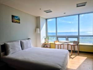 仁川市Cozy - Sunny Studio的一间卧室,配有一张床、一张桌子和一扇大窗户