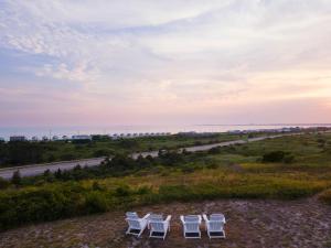four white chairs on a hill with a road at Dune Crest Hotel in North Truro