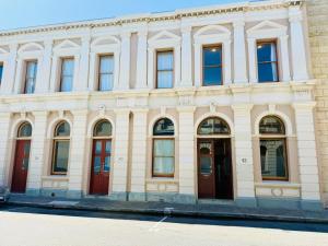 a white building with red doors and windows at 42 Lilys Central Heritage Westend in Fremantle