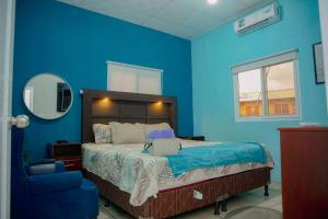 Un dormitorio azul con una cama y una silla. en Casa Sto Tomas, en Puerto Santo Tomás de Castilla 10 fotos más