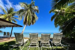 a group of chairs sitting on the beach at Fare Matairoa - 2BR Beach Cottage in Iumaru