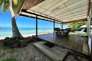 a wooden porch with a table and chairs on the beach at Fare Matairoa - 2BR Beach Cottage in Iumaru +14 photos