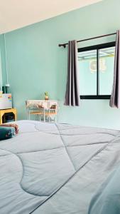 een groot wit bed in een kamer met een tafel bij เอ็นแอนด์พี รีสอร์ทบุรีรัมย์ in Ban Don Wai