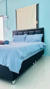 a large bed with blue sheets and blue pillows at เอ็นแอนด์พี รีสอร์ทบุรีรัมย์ in Ban Don Wai
