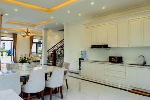 a kitchen with white cabinets and a table and chairs at Villa Măng Lin Đà Lạt in Da Lat