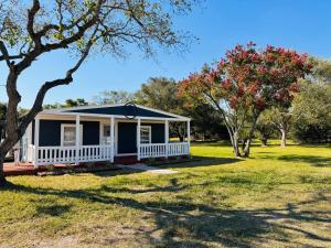 a house with a porch in a field with trees at The Blue Oasis - Palm & Pool Retreat in Pearland