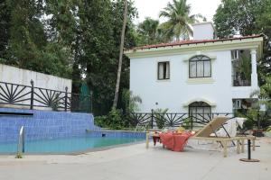 a white house with a table and a pool at The Hideout By NK in Assagao +32 photos