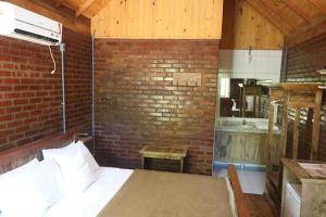 a bedroom with a brick wall and a bed in a room at A Cabana Chalé & Pousada - Especializada em Grupos até 40 Pax- in Canela