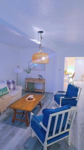 Una sala de estar con sillas azules y una mesa. en the paradise house 10 minutes from the beach, en North Rose