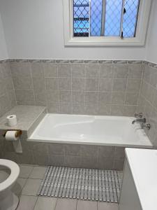 a bathroom with a tub and a toilet at Double room with shared bathoom in Auburn