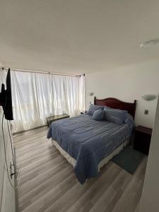 a bedroom with a bed with a blue blanket at Espectacular Depto en Cavancha in Iquique