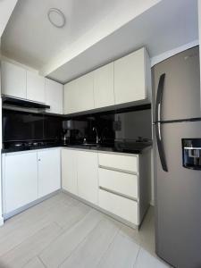 a kitchen with white cabinets and a refrigerator at Hermoso Apartamento Nuevo con Excelente Vista in Ibagué