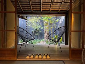 2 chaises assises sur une terrasse couverte avec une fenêtre dans l'établissement Rinn Kishoan, à Kyoto