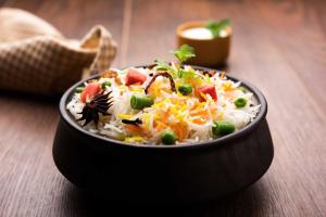 a bowl of rice with vegetables and cheese on a table at Super Collection O Vastukar Retreat in Bhubaneshwar