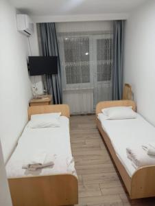 two beds in a room with a window at Qorjyn Hotel in Shymkent