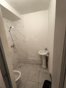 a white bathroom with a toilet and a sink at Qorjyn Hotel in Shymkent