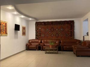 a living room with brown leather couches and a rug at Qorjyn Hotel in Shymkent