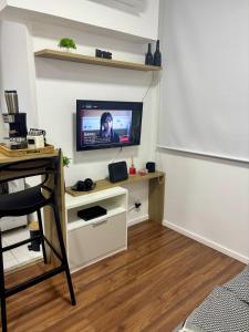 a living room with a tv on a wall at Studio Home Office Completo Cama Queen e Ar Condicionado Vista Panorâmica in Mogi das Cruzes
