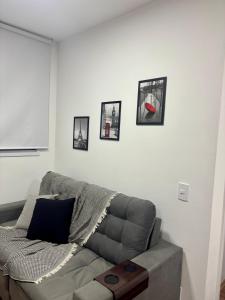 a living room with a couch and pictures on the wall at Studio Home Office Completo Cama Queen e Ar Condicionado Vista Panorâmica in Mogi das Cruzes